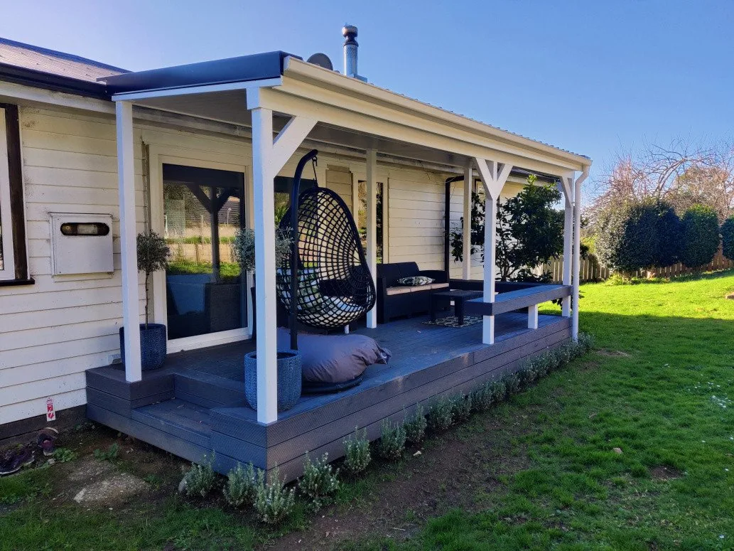 A premium pine wide board deck with a white-posted pergola against a weatherboard house